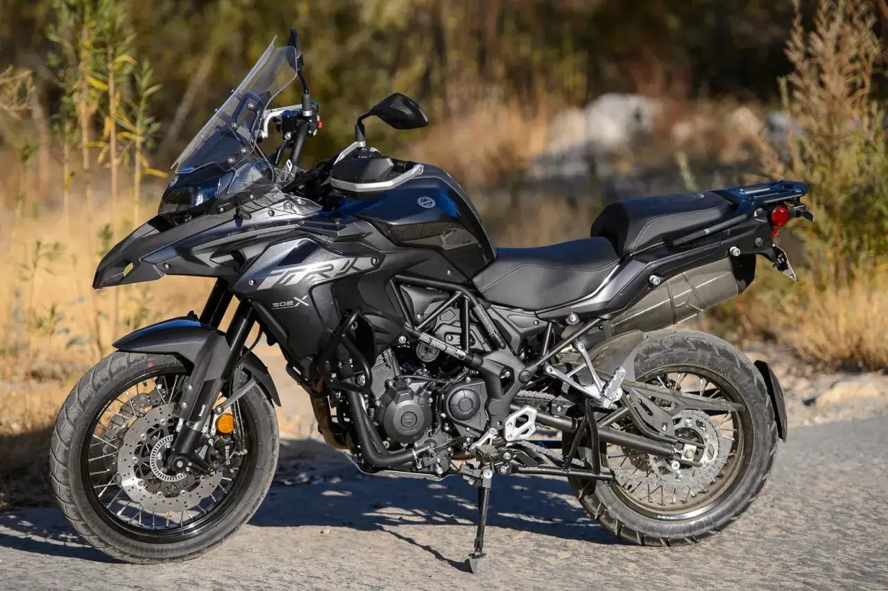 Czarny motocykl Benelli TRK 502X gotowy na przygodę na tle dzikiej przyrody.