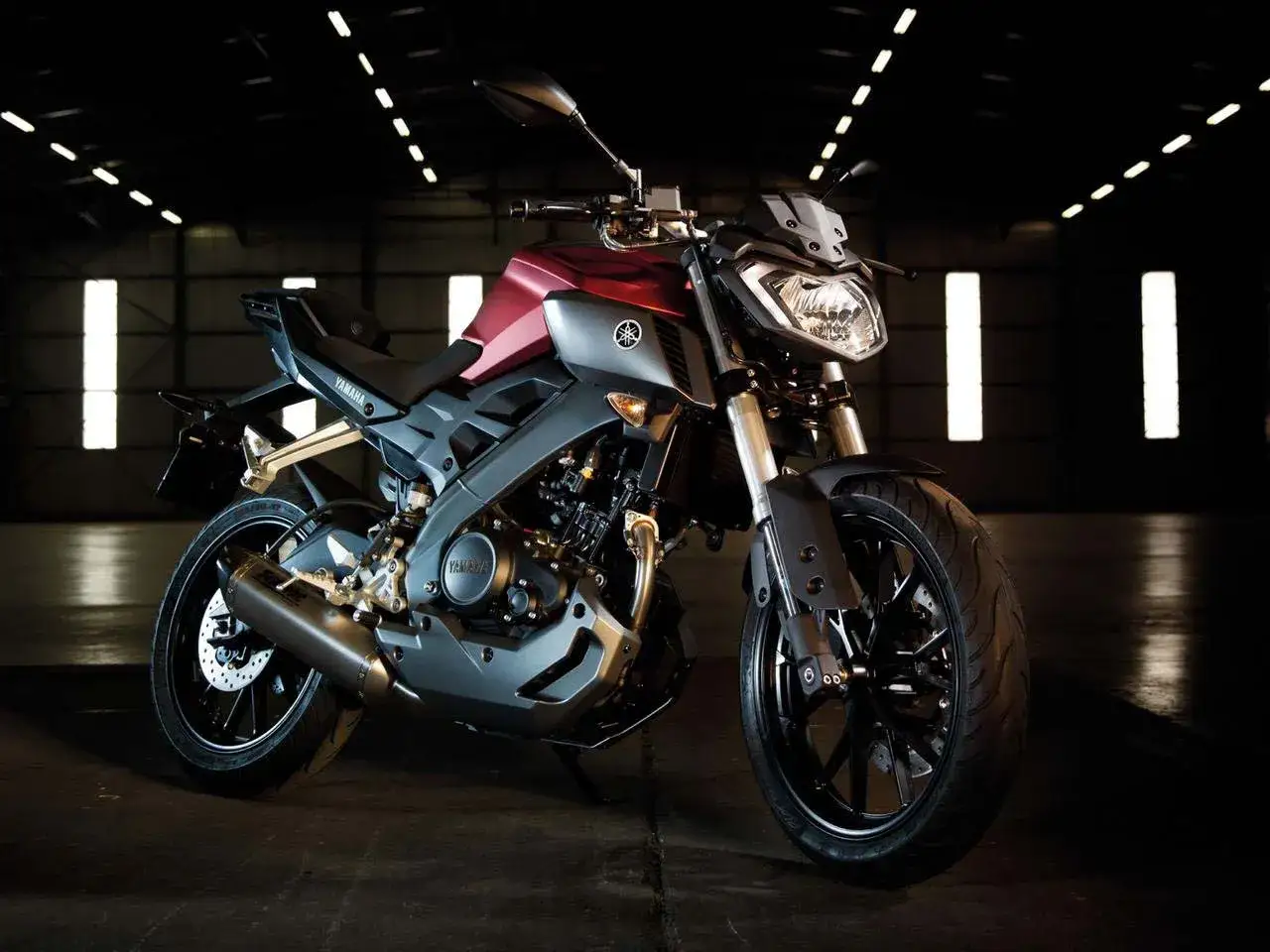 Czerwono-szary motocykl Yamaha MT 125 v max w ciemnym pomieszczeniu, gotowy do jazdy.