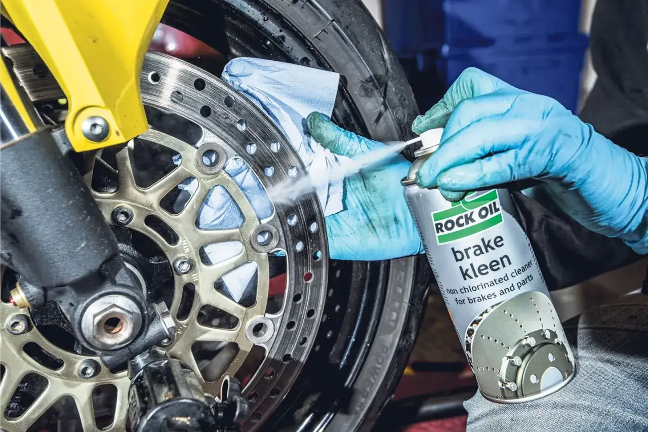 Rękawiczki i chusteczka pomagają w czyszczeniu hamulców motocykla. Spray 